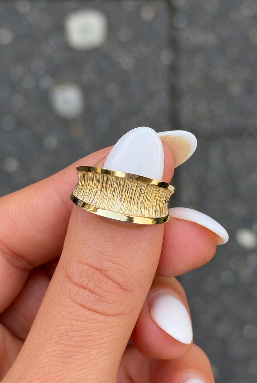 Retuschiertes Produktfoto des goldenen Rings Derin mit gesäubertem Zeigefingernagel